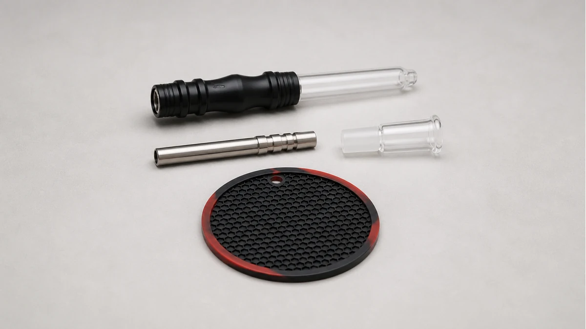 A manual nectar collector laid out with its removable tip, body, mouthpiece and heat-safe work surface
