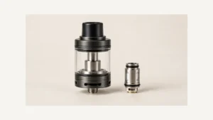 Complete empty glass vape tank beside a separate premade coil head