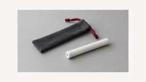Plain white ceramic one hitter tube beside empty cloth sleeve