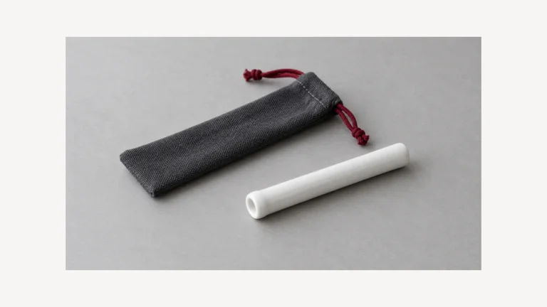 Plain white ceramic one hitter tube beside empty cloth sleeve