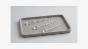 Three solid clear glass tools resting separately on a tray